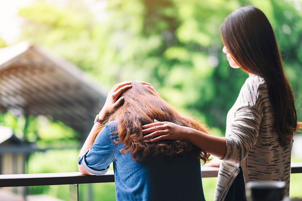 a woman comforts and consoles her friend who suffers from depression
